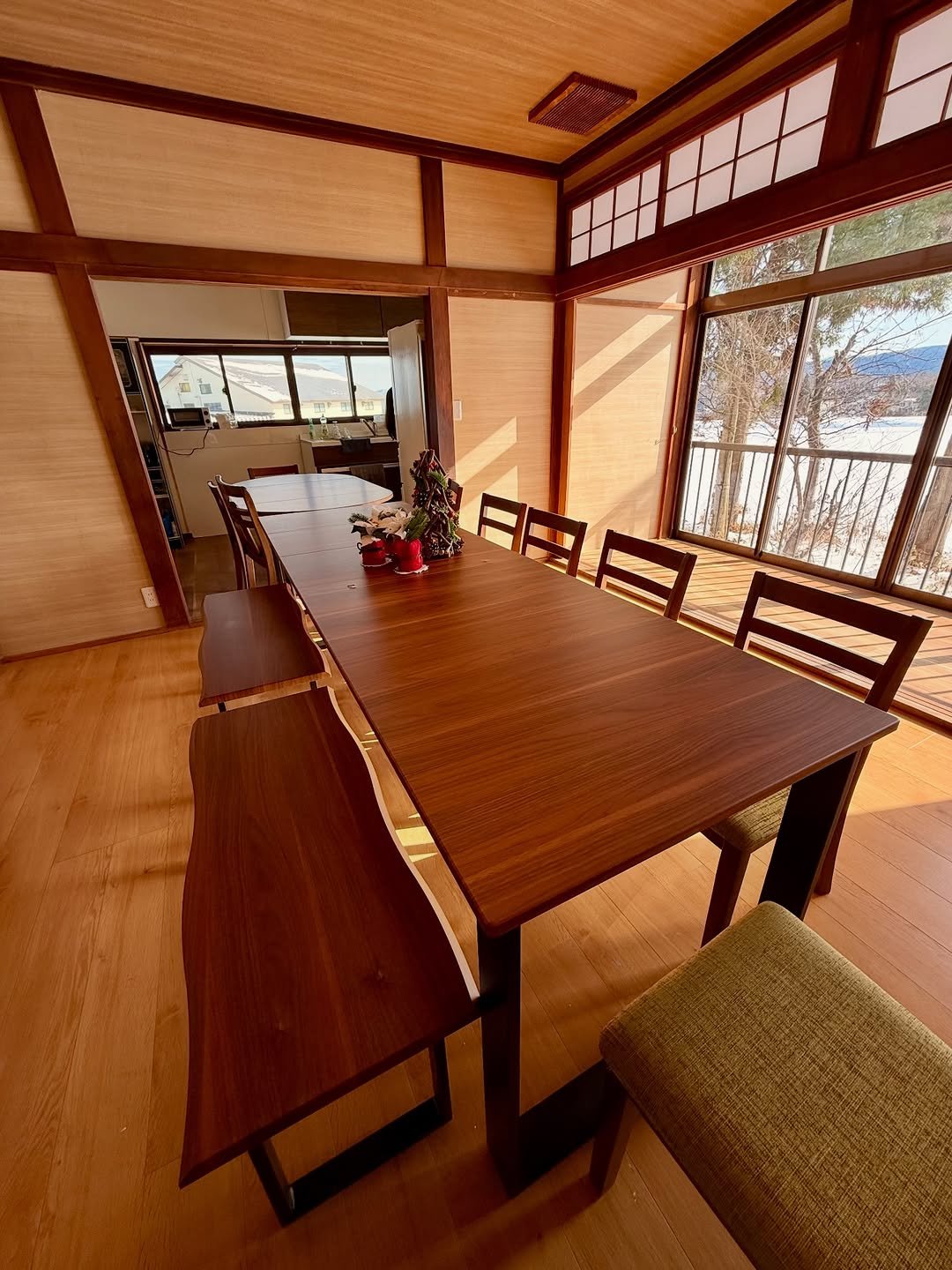 The long dining table set for a group, snow visible through the balcony doors.